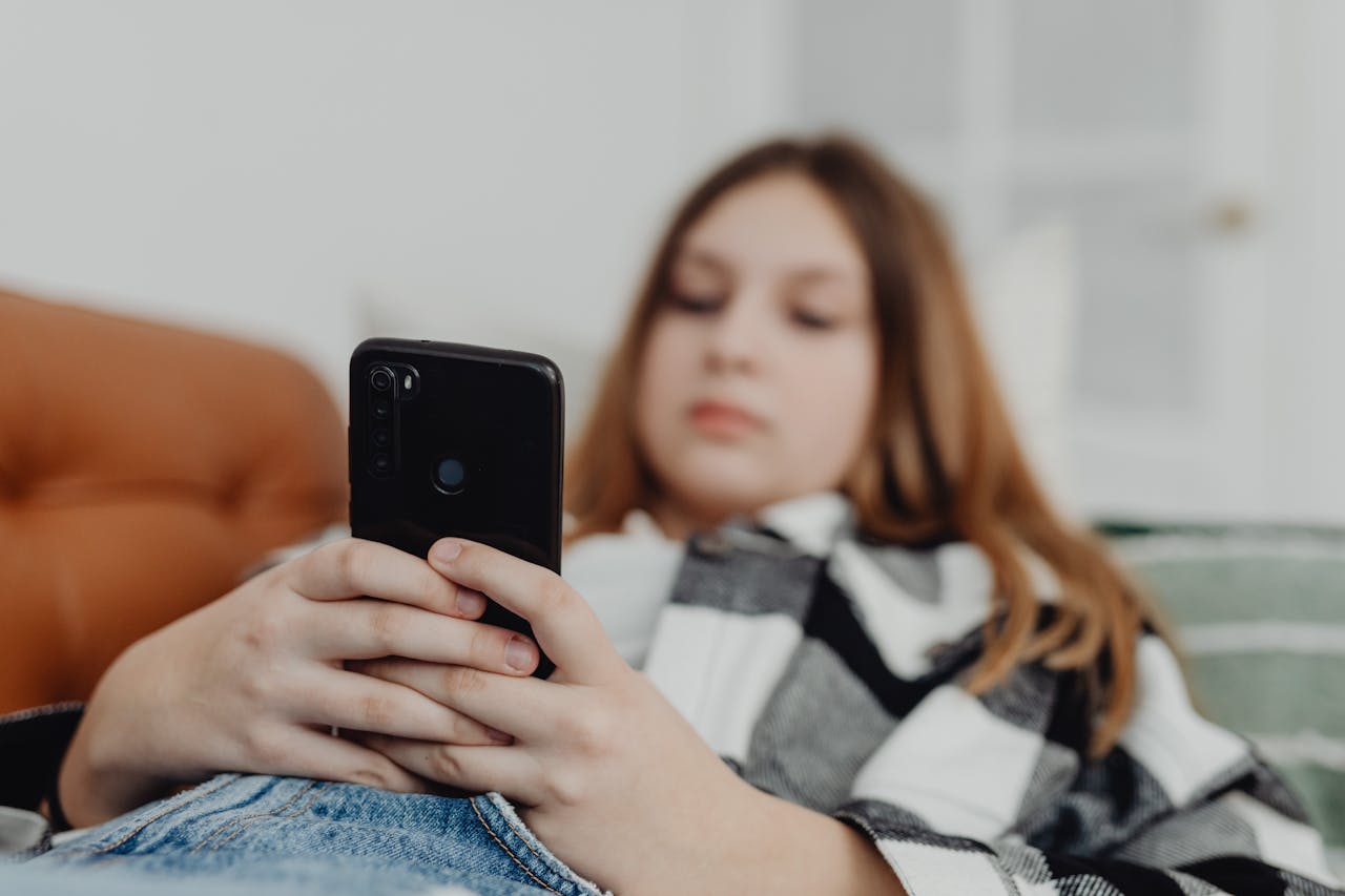 adolescente utilisant son smartphone sur les réseaux sociaux pouvant favoriser anxiété et troubles du sommeil