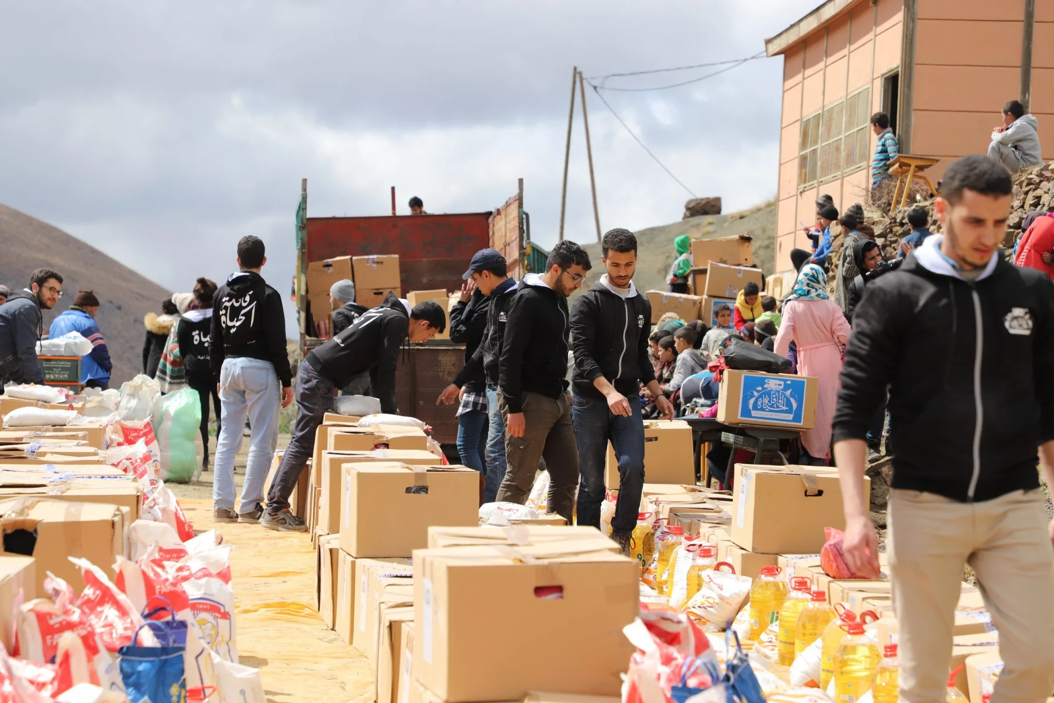 Étudiants bénévoles distribuant des aides alimentaires lors de la Caravane Al Hayat dans un douar de la région d’Azilal