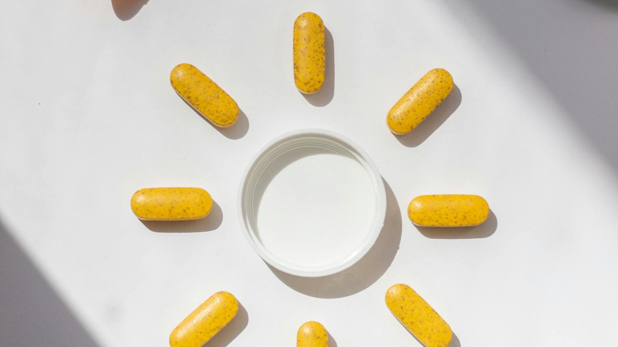 gélules de collagène disposées en cercle autour d’un pot pour illustrer les compléments alimentaires anti-âge