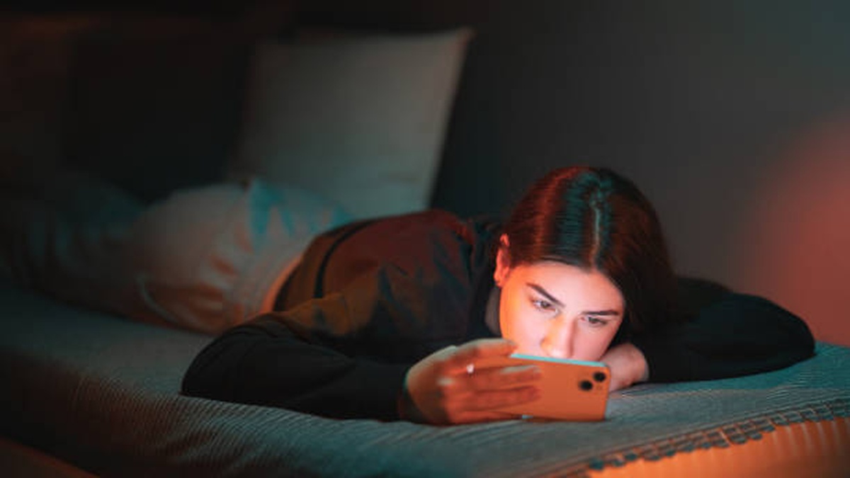 Adolescente utilisant un smartphone tard le soir, illustrant le manque de sommeil chez les adolescents.