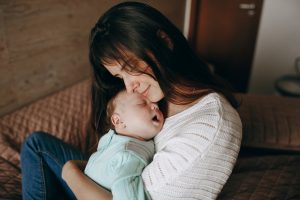 Mère tenant son bébé endormi contre elle en train de lui chanter une comptine dans un moment de tendresse
