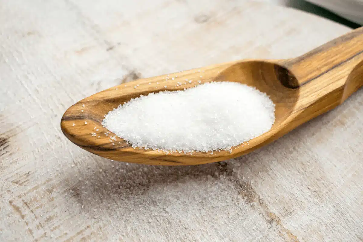 Édulcorant sucralose en poudre dans une cuillère en bois, utilisé comme alternative au sucre dans les produits sans sucre