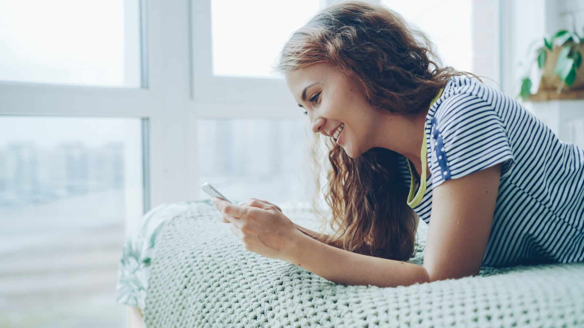Une personne sur un canapé avec son smartphone en scrolling